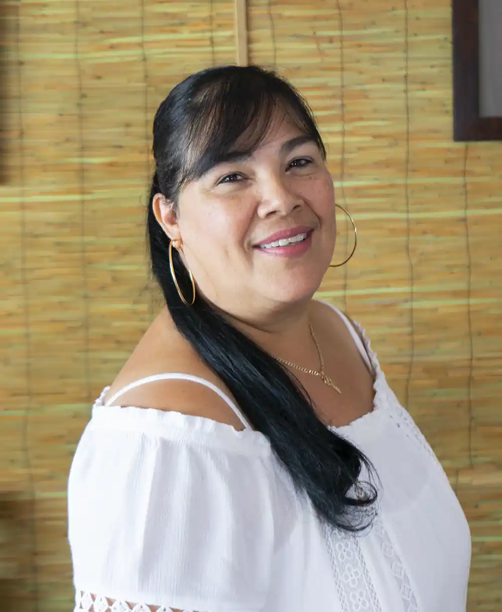 woman with dark hair smiling near a bamboo wall in an acupuncture office in key west