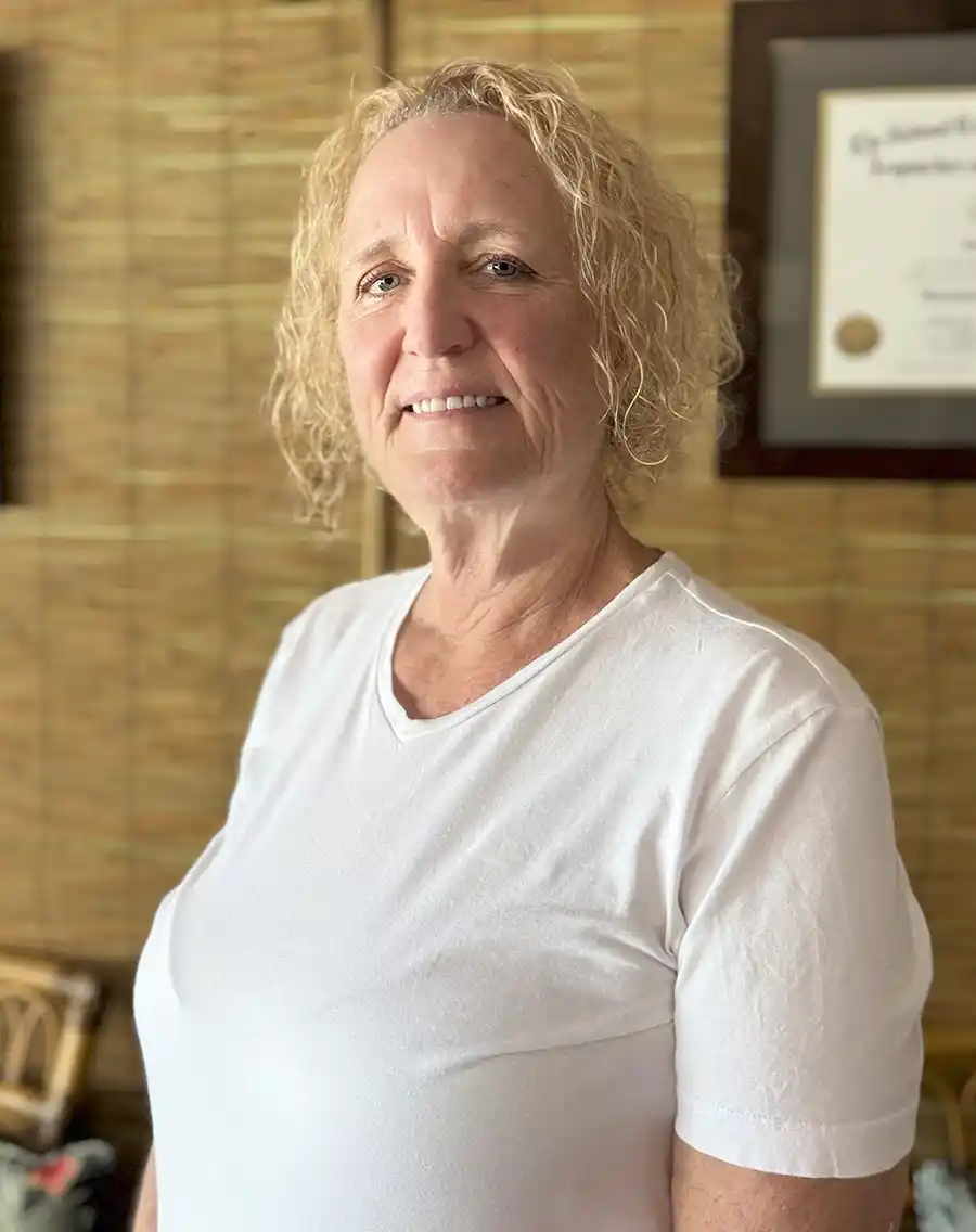 blonde curly haired female doctor at an acupuncturist office in key west next to a bambook wall smiling