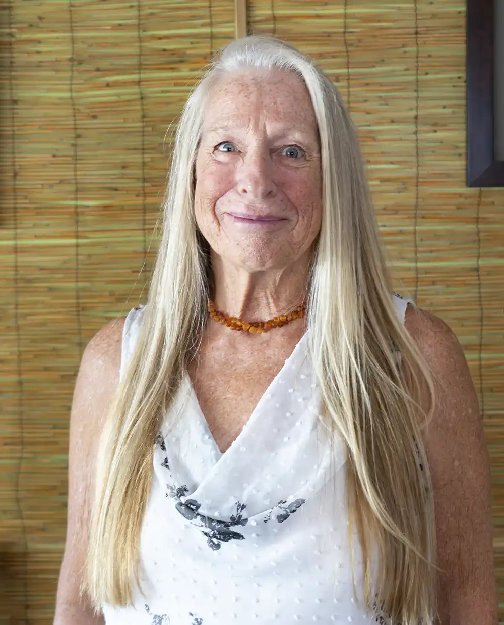 woman standing by a bamboo wall smiling acupuncture office