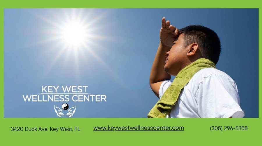 man looking up to sun in heat of summer outside white shirt blue sky