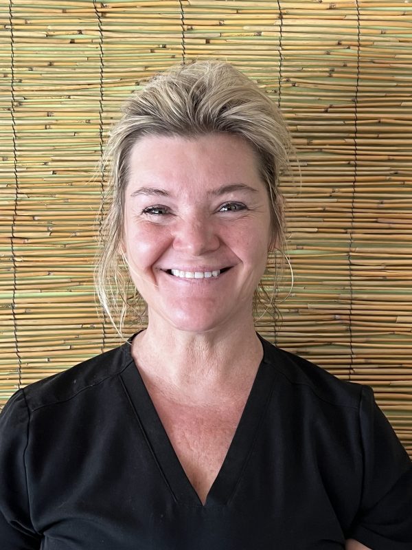 massage therapist next to a bamboo wall