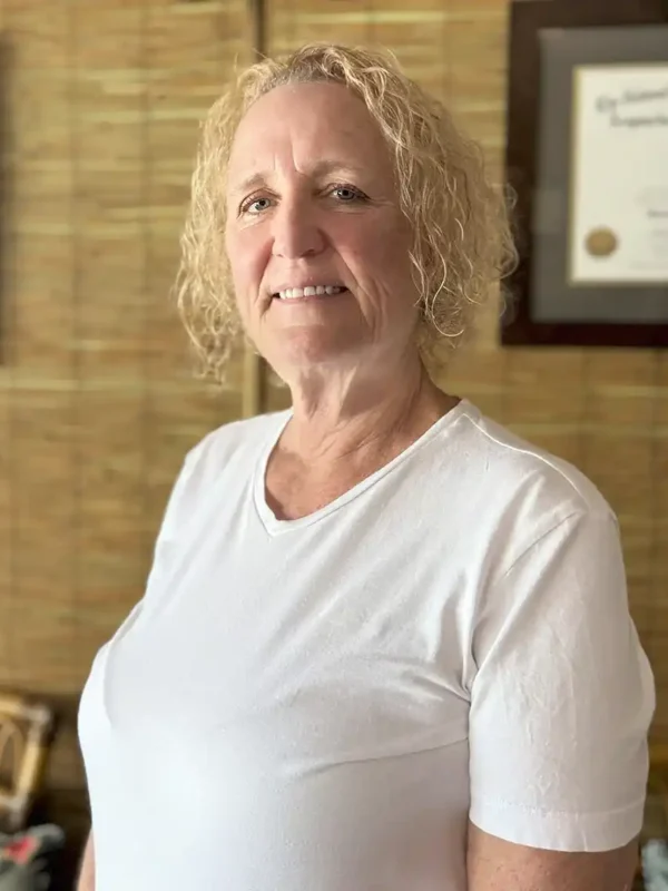 blonde curly haired female doctor at an acupuncturist office in key west next to a bambook wall smiling
